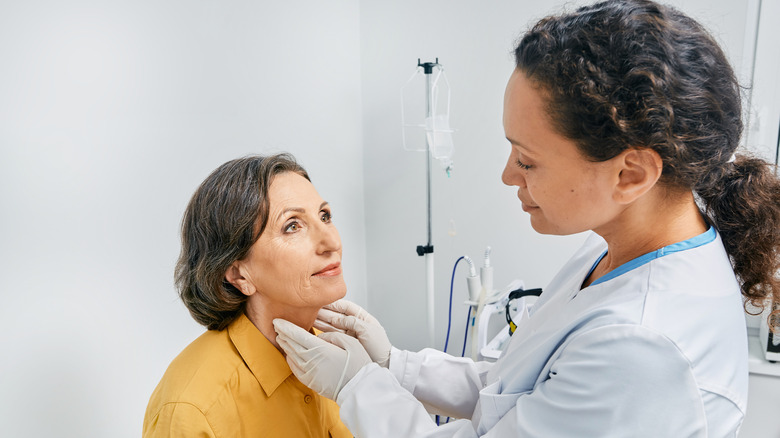 Doctor palpating woman's neck