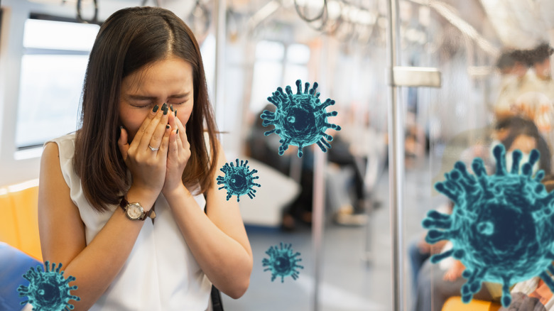 Woman sneezing on bus surrounded by virus cells