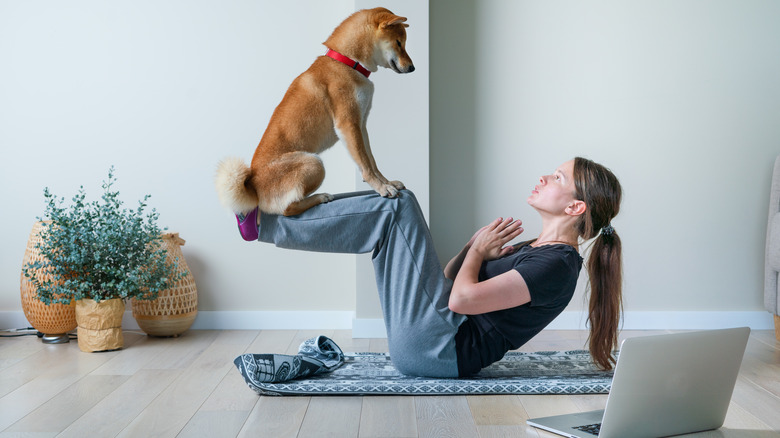 woman practicing yoga with dog
