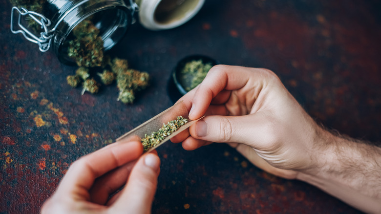 man's hands rolling marijuana cigarette