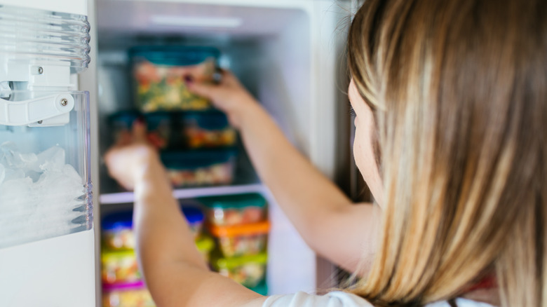 woman putting container into freezer