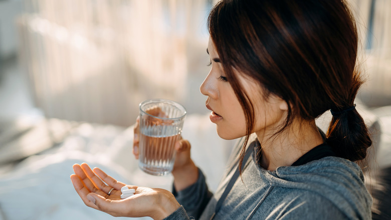 woman taking pills and holding glass of water