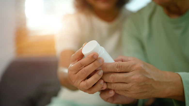 man and woman reading pill bottle label