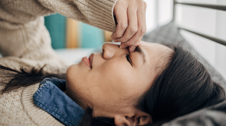 woman pinching nose with headache