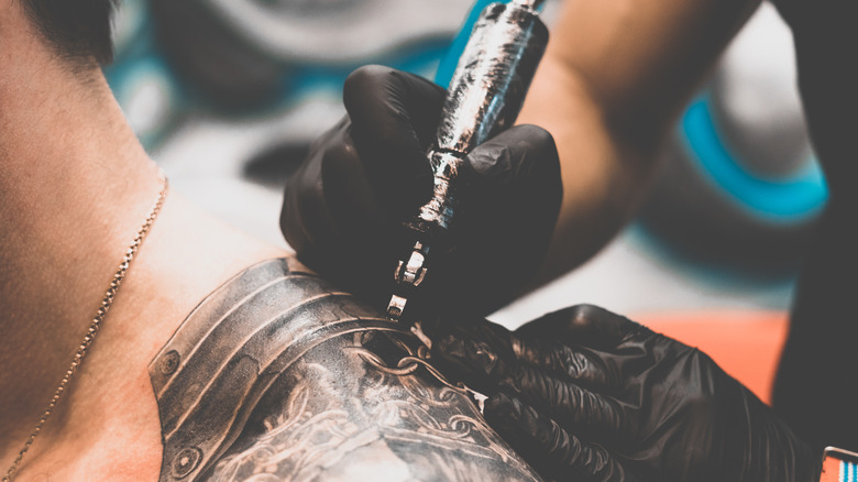 Hand holding a tattoo gun while applying ink to skin