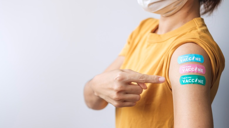 Woman pointing to vaccine bandaids on arm