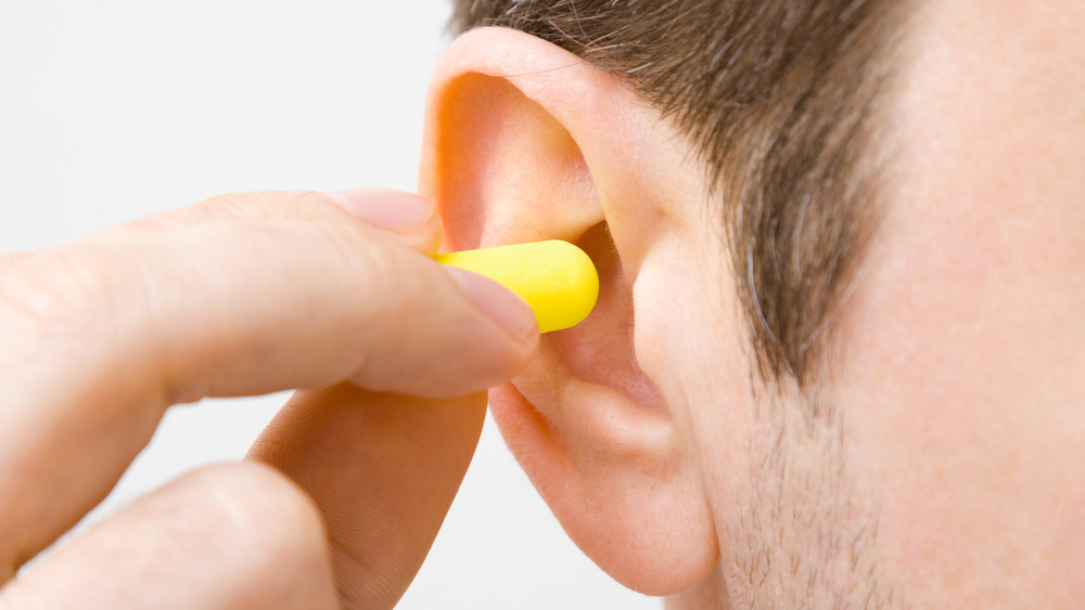 Person putting yellow earplug into ear