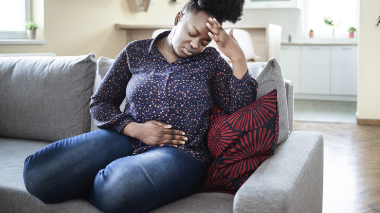 woman holding stomach on couch