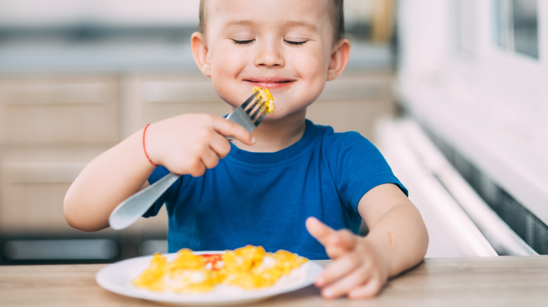 young boy eating an omelet