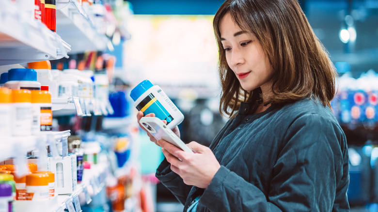 A woman looking at a medication label at the pharmacy