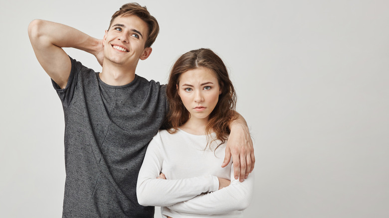 Carefree man with arm around frustrated woman