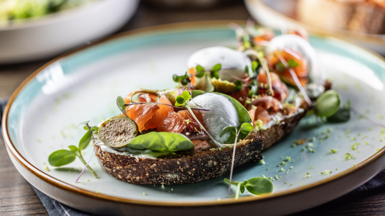 A slice of sourdough bread topped with salmon and herbs