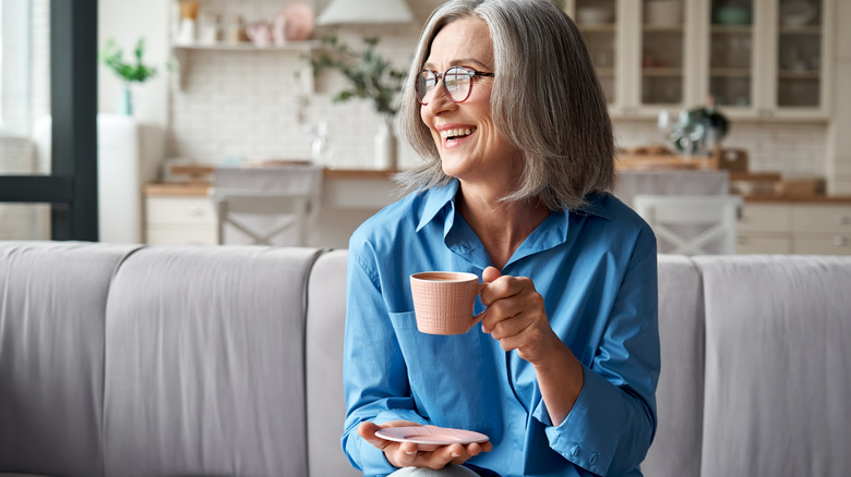 An older woman drinks a cup of coffee