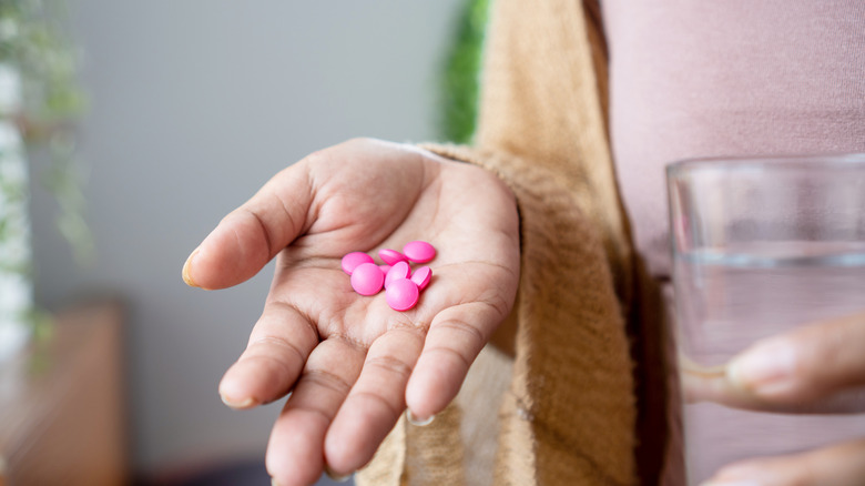 Someone holds a handful of pink pills