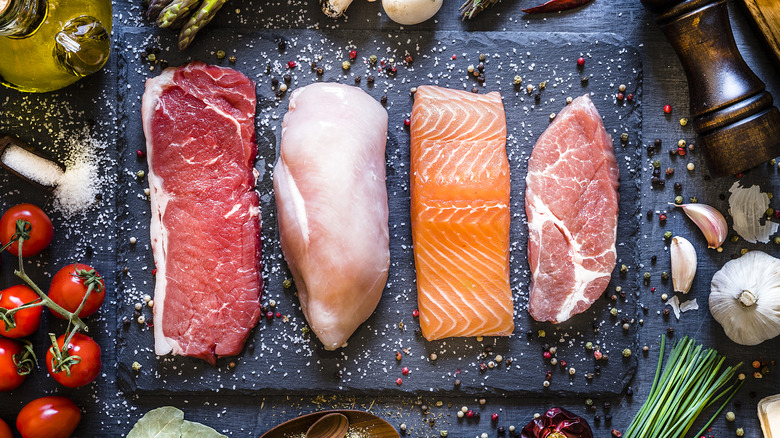 chicken, salmon, and beef on a black plate