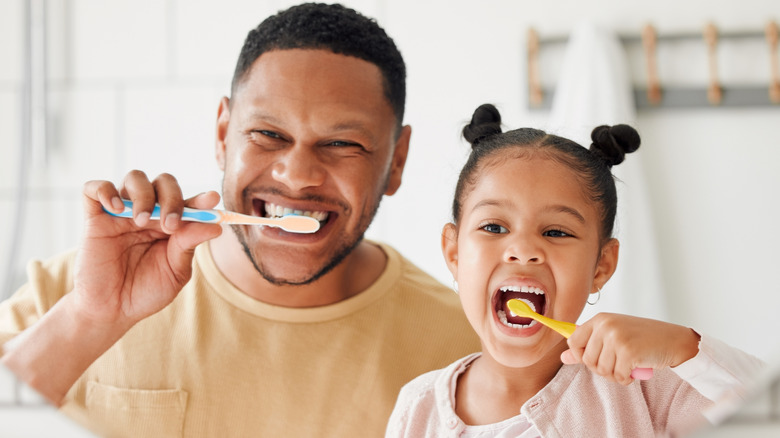 Father and daughter brushing teeth