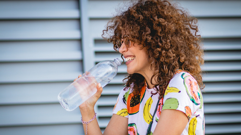 Smiling woman drinking water bottle