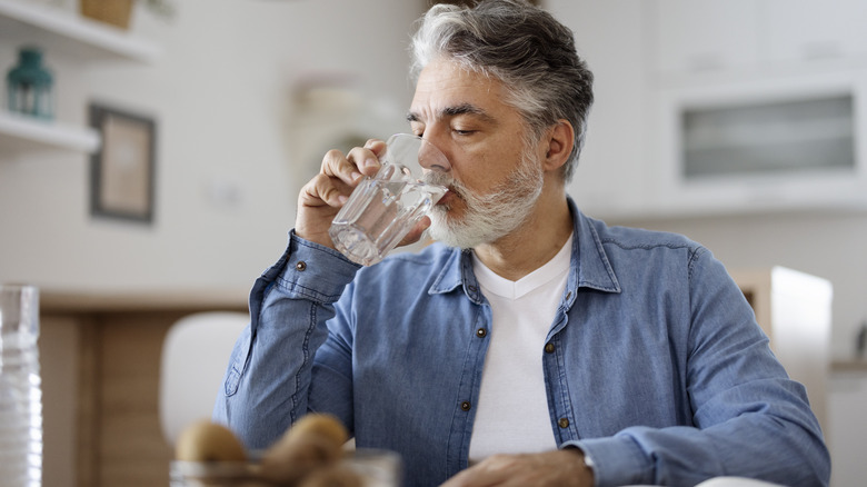 man drinking water in his kitchen