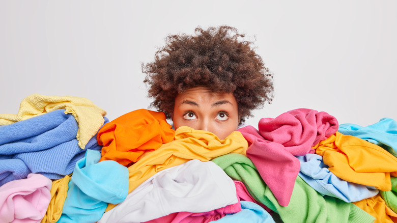 woman's face behind clothing pile