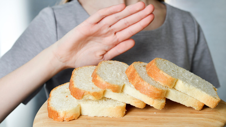woman putting hand up to reject bread slices on board
