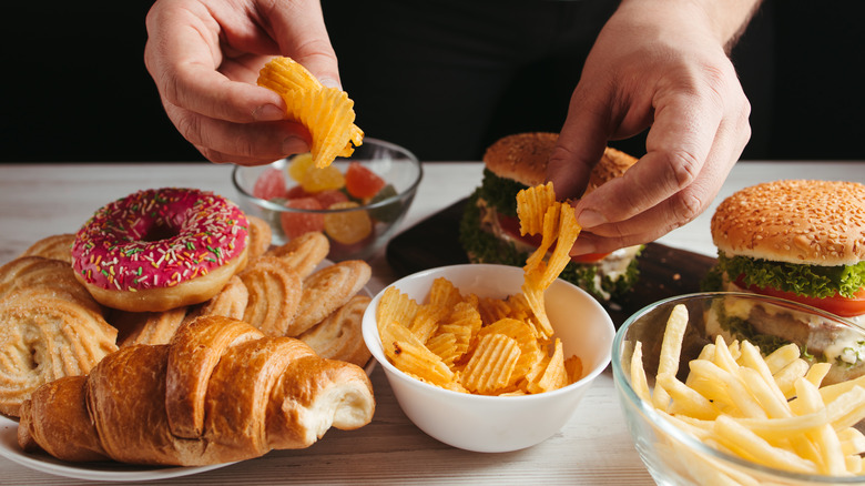 hands grabbing chips on junk food table