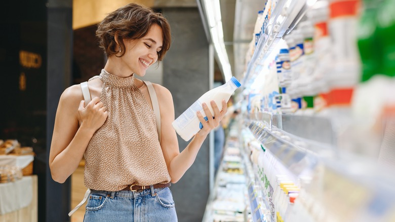 woman looking at label on bottle in supermarket