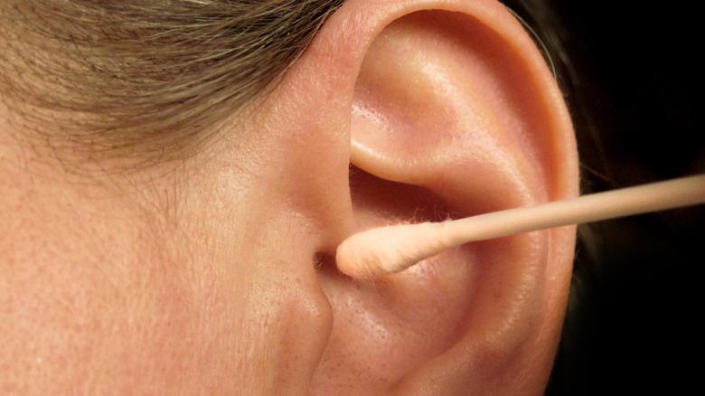 Close-up of cotton swab cleaning outside of ear