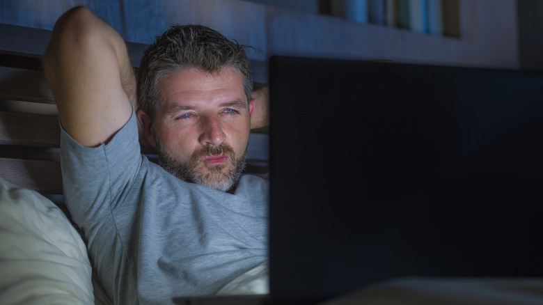 man watching video in bed