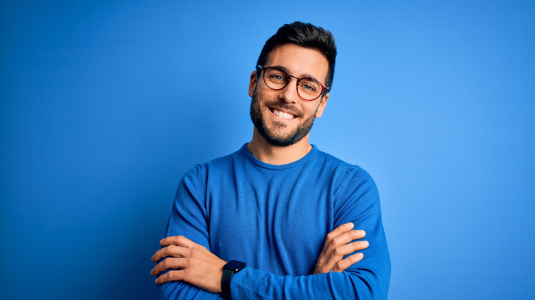 Man with beard wearing glasses with arms crossed, smiling