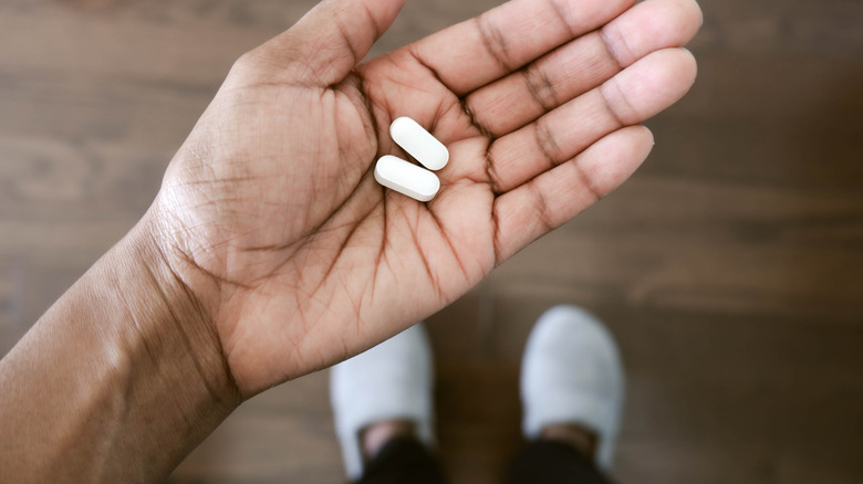 woman holding ibuprofen pills in hand