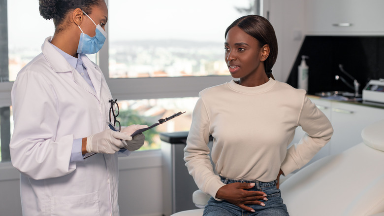 Doctor consulting with patient holding stomach