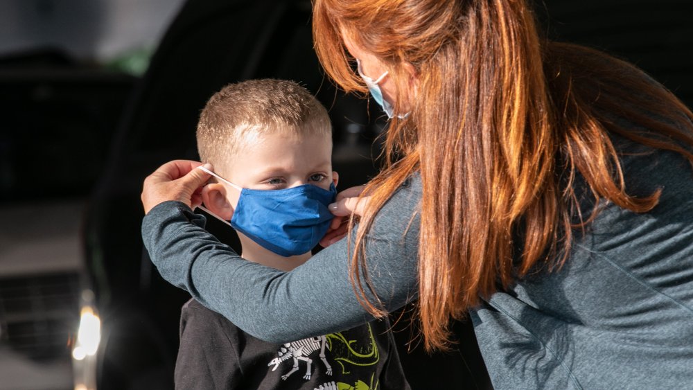 Woman helps a young boy with a face mask