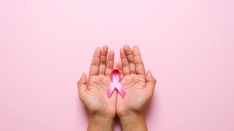 Someone holds a pink cancer ribbon