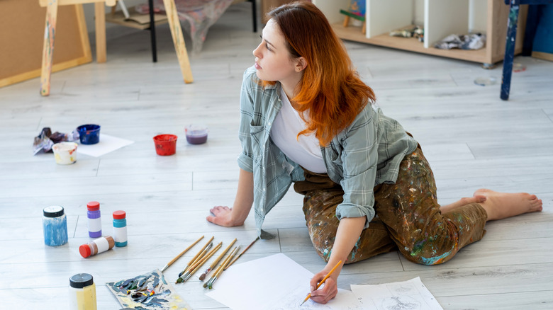 Woman painting and sketching on floor