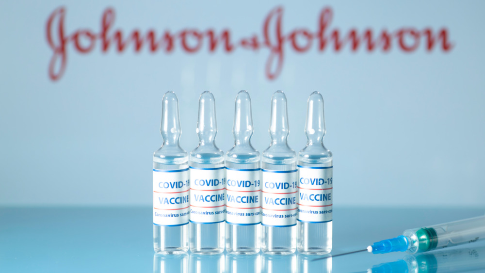 Vaccine vials in front of a Johnson and Johnson sign