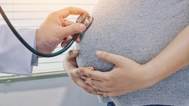 Pregnant woman at the doctor, listening to baby with stethoscope