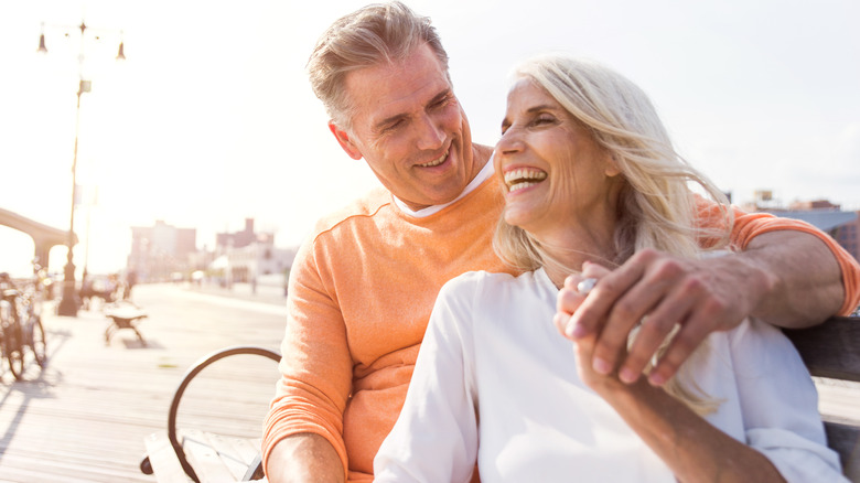 Older couple laughing sitting on bench