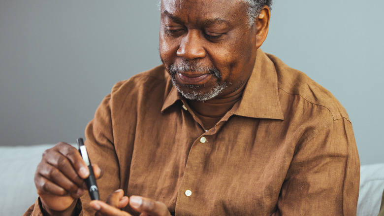 senior black man checking blood sugar