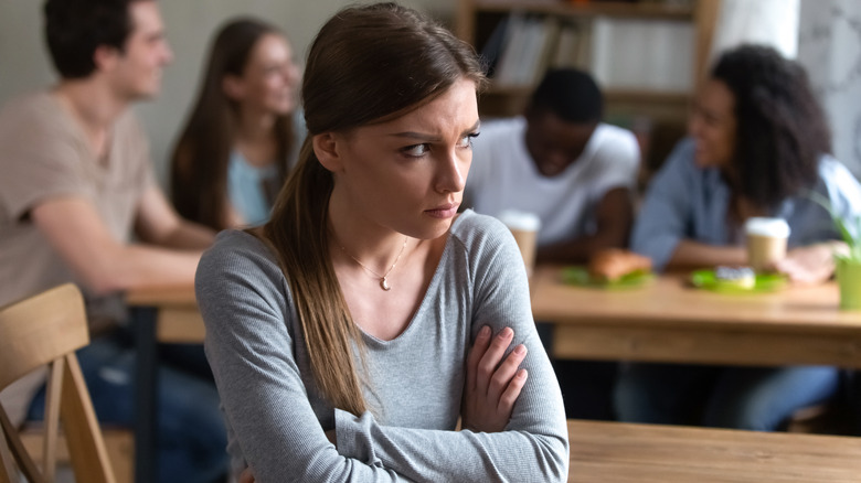 Young woman sitting alone with crossed arms 