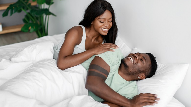 Man and woman smiling in bed