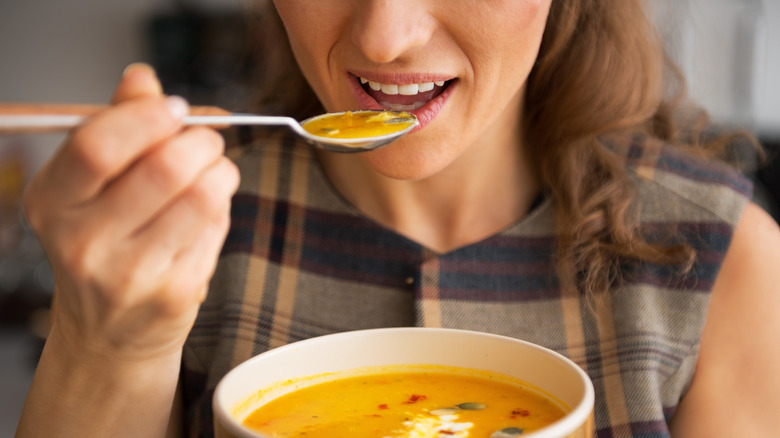 Woman eating spoonful of soup