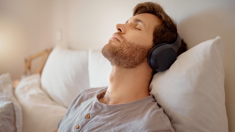 Man relaxing in bed with headphones on