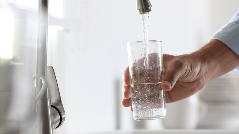 hand filling a glass of water from a sink