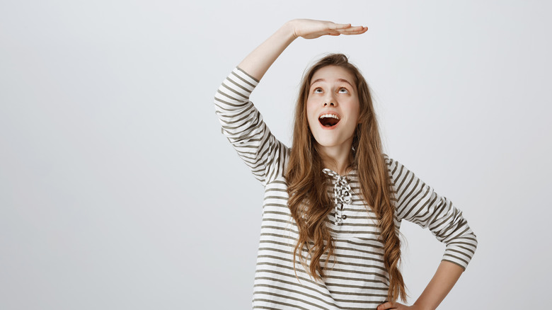 woman with hand over her head indicating height