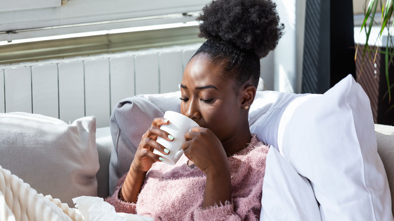 Sick woman drinking from mug