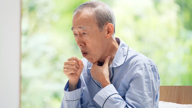 Elderly man in pajamas coughing