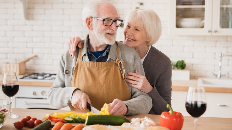 an elderly couple chopping vegetables 