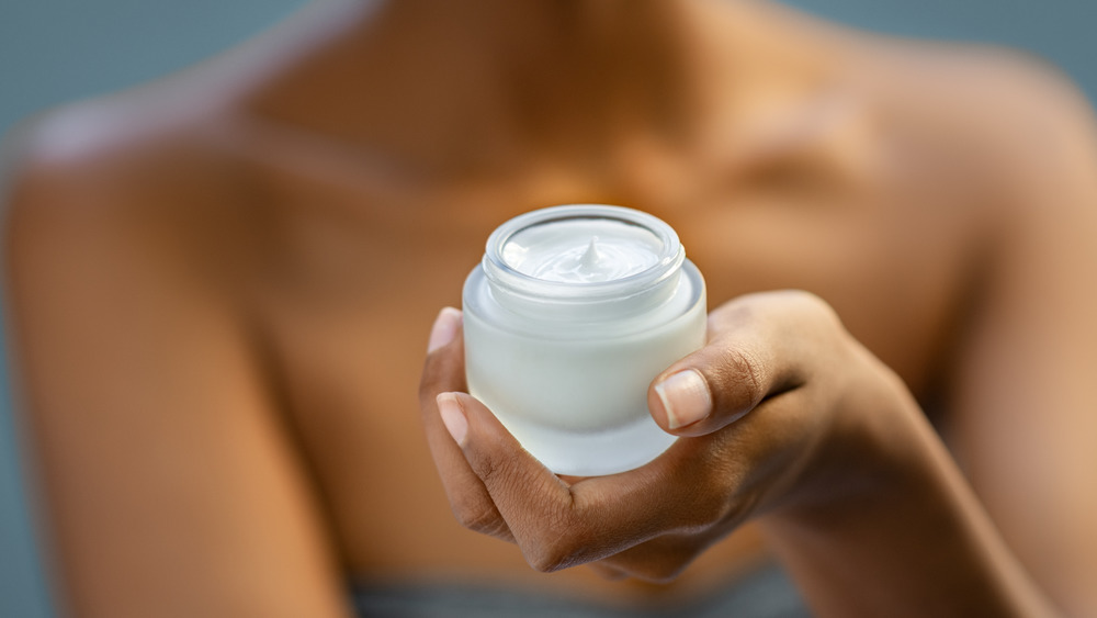 woman holding a pot of lotion