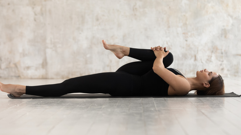 woman doing knee to chest pose for back pain relief