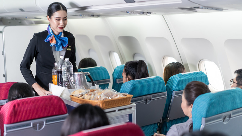 a flight attendant passing out snacks